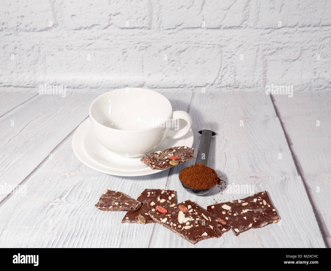 Eine weiße Tasse mit dunkler Schokolade Brammen und ein Maß für gemahlenen Kaffee Stockfoto