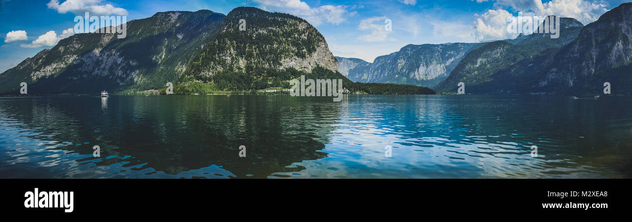 Einen wunderschönen Blick auf den berühmten Hallstätter See mit leuchtenden grünen Bergen im Hintergrund an einem sonnigen Tag im Sommer mit blauem Himmel und Wolken, Hallst Stockfoto