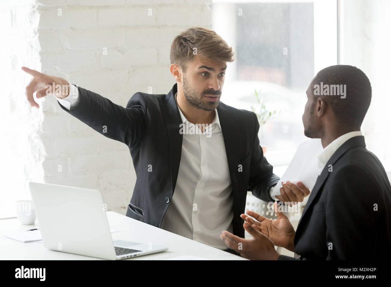 Unhöflich weißen Partner erzählen schwarzer Geschäftsmann aus seinem Büro Stockfoto