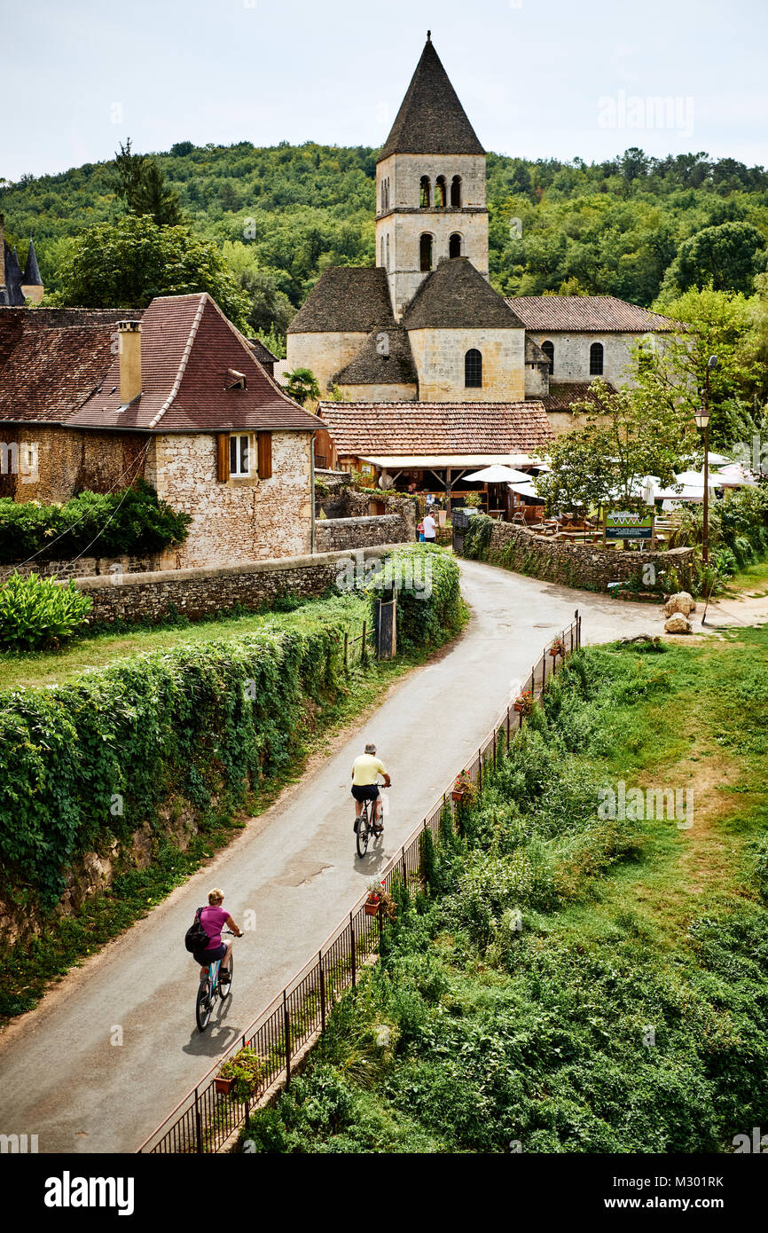 Radfahren an der Eglise Romane in St. Leon sur Vezere in der Dordogne Frankreich aufgeführt als eines der schönsten Dörfer von Frankreich Stockfoto