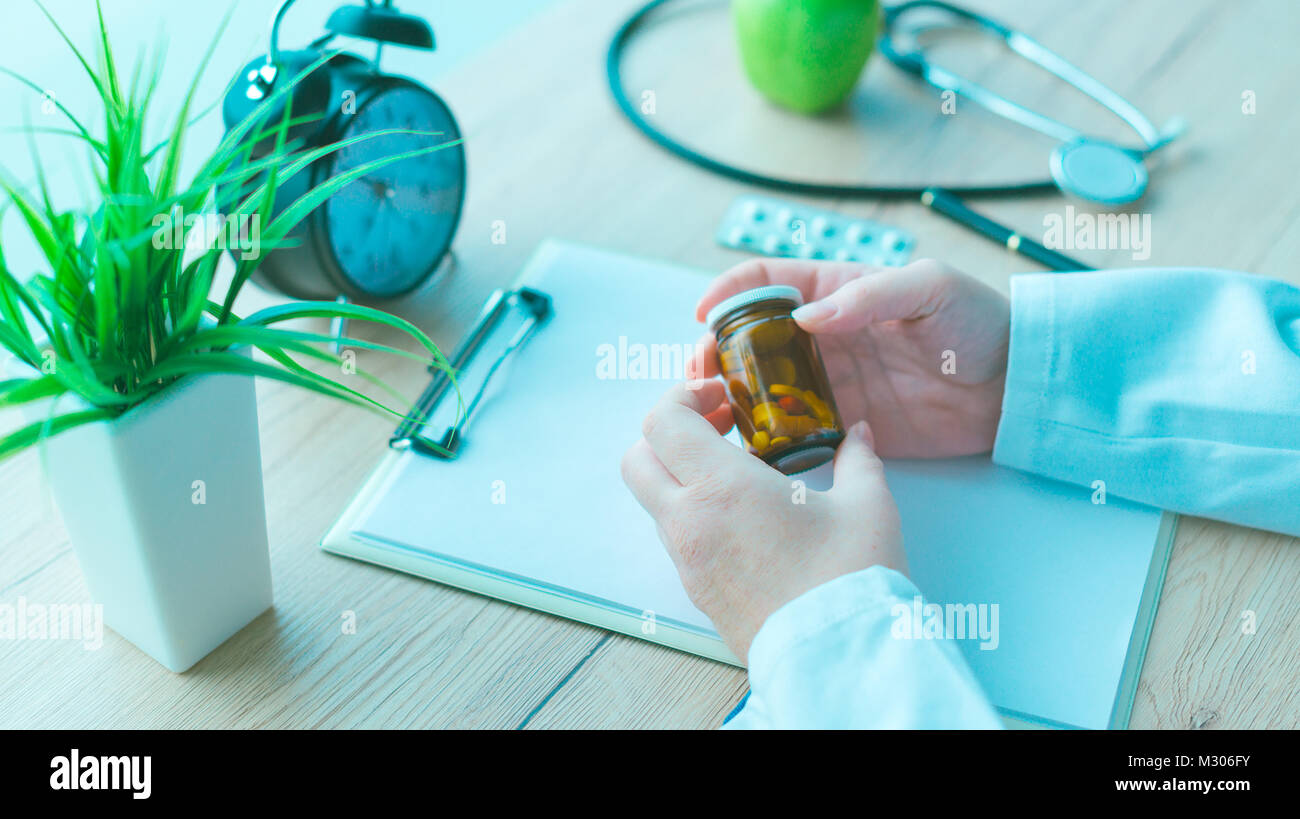 Hausarzt Holding unbeschrifteten Flasche verschiedene Pillen und Medikamente, Generika Konzept, Medizin und Gesundheitswesen, blau getönt Stockfoto