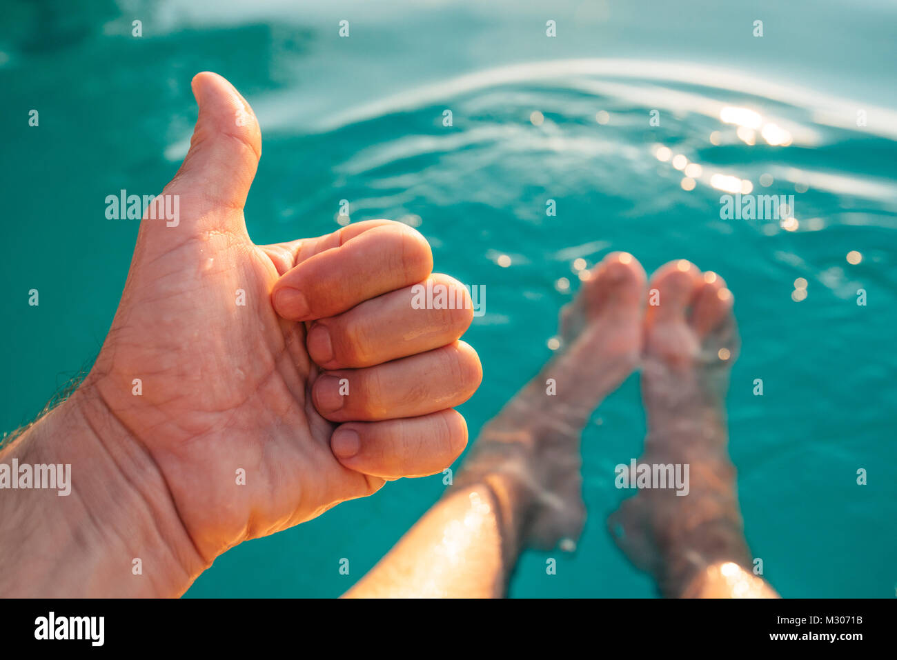 Männliche geben Daumen hoch, beim Schwimmen im Außenpool. Mann genießen Sie erfrischende Pool Wasser im Sommer Sonnenuntergang. Ferien und Wochenende. Stockfoto