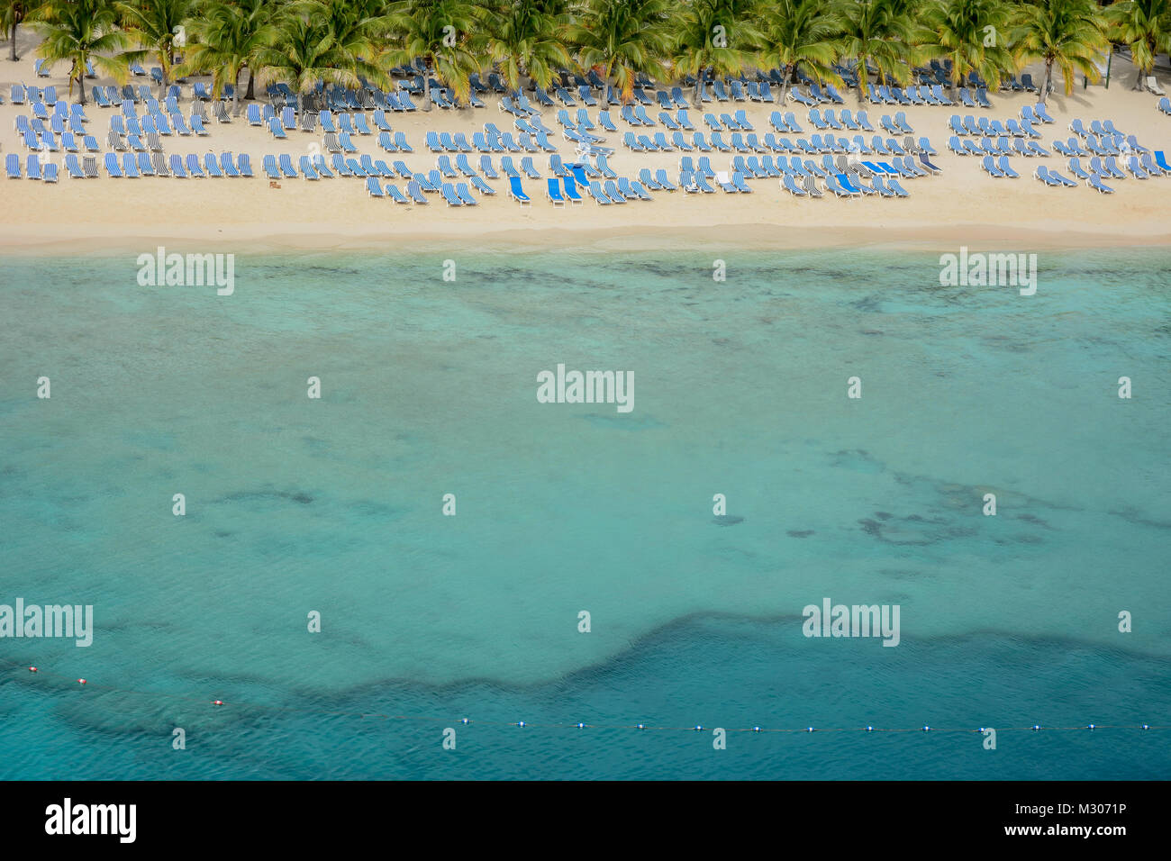 Liegestühle am weißen Sandstrand von türkisblauem Meer Stockfoto