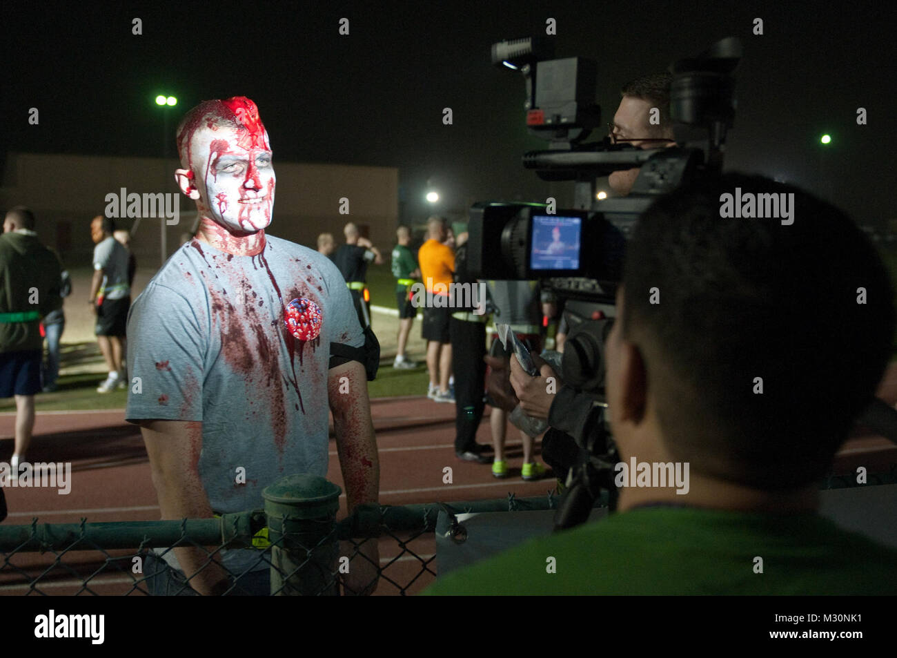 Mitglieder der 12. Öffentlichen Angelegenheiten Loslösung inverviewd Spc. Alex Neeley, wie er immer zuerst einen Geschmack für die dritte Armee Fleisch wie ein Zombie in der Nacht von Dez. 22 entwickelt. Zombie Laufen 2012-04 von 316 ESC Stockfoto