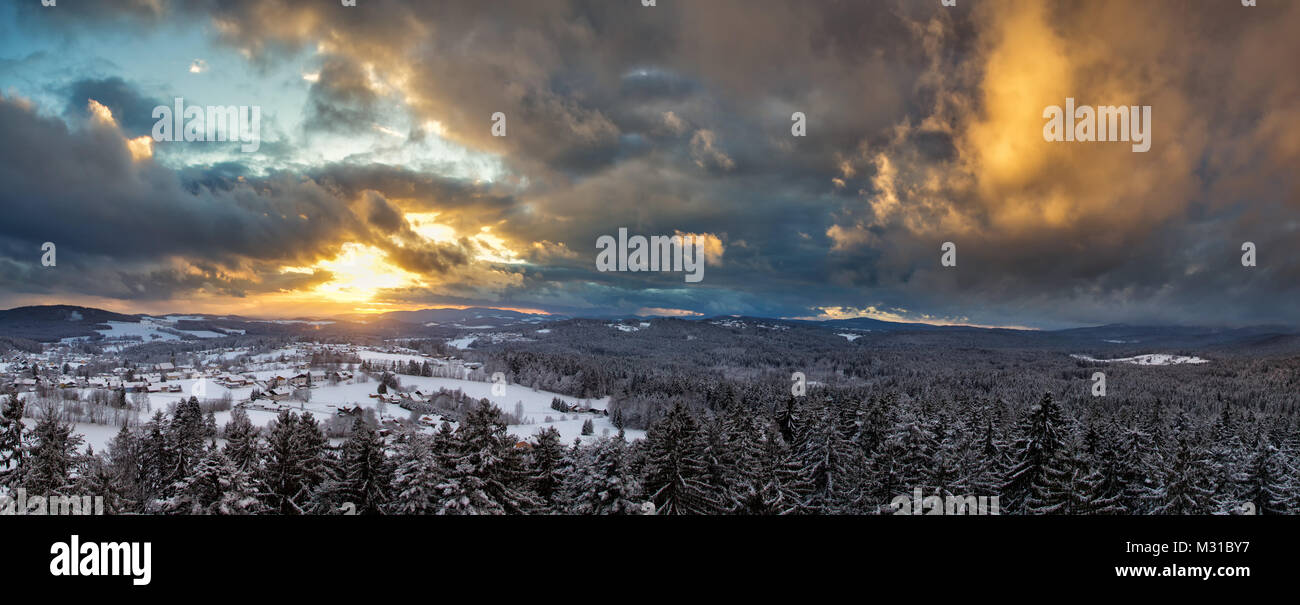 Sonnenuntergang mit dramatischen Himmel über die winterliche Landschaft in der Nähe von Neuschönau im Nationalpark Bayerischer Wald in Bayern, Deutschland. Stockfoto