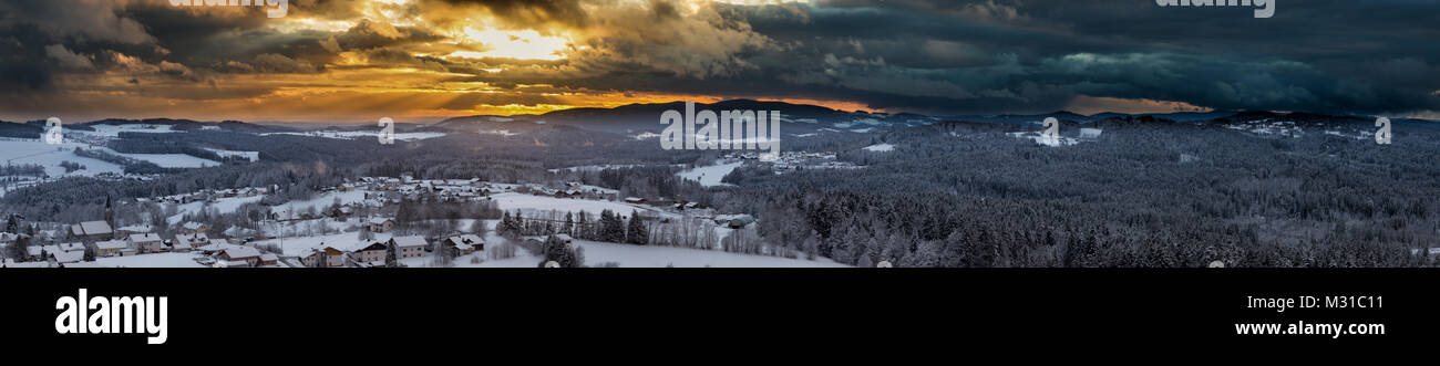 Sonnenuntergang mit dramatischen Himmel über die winterliche Landschaft in der Nähe von Neuschönau im Nationalpark Bayerischer Wald in Bayern, Deutschland. Stockfoto