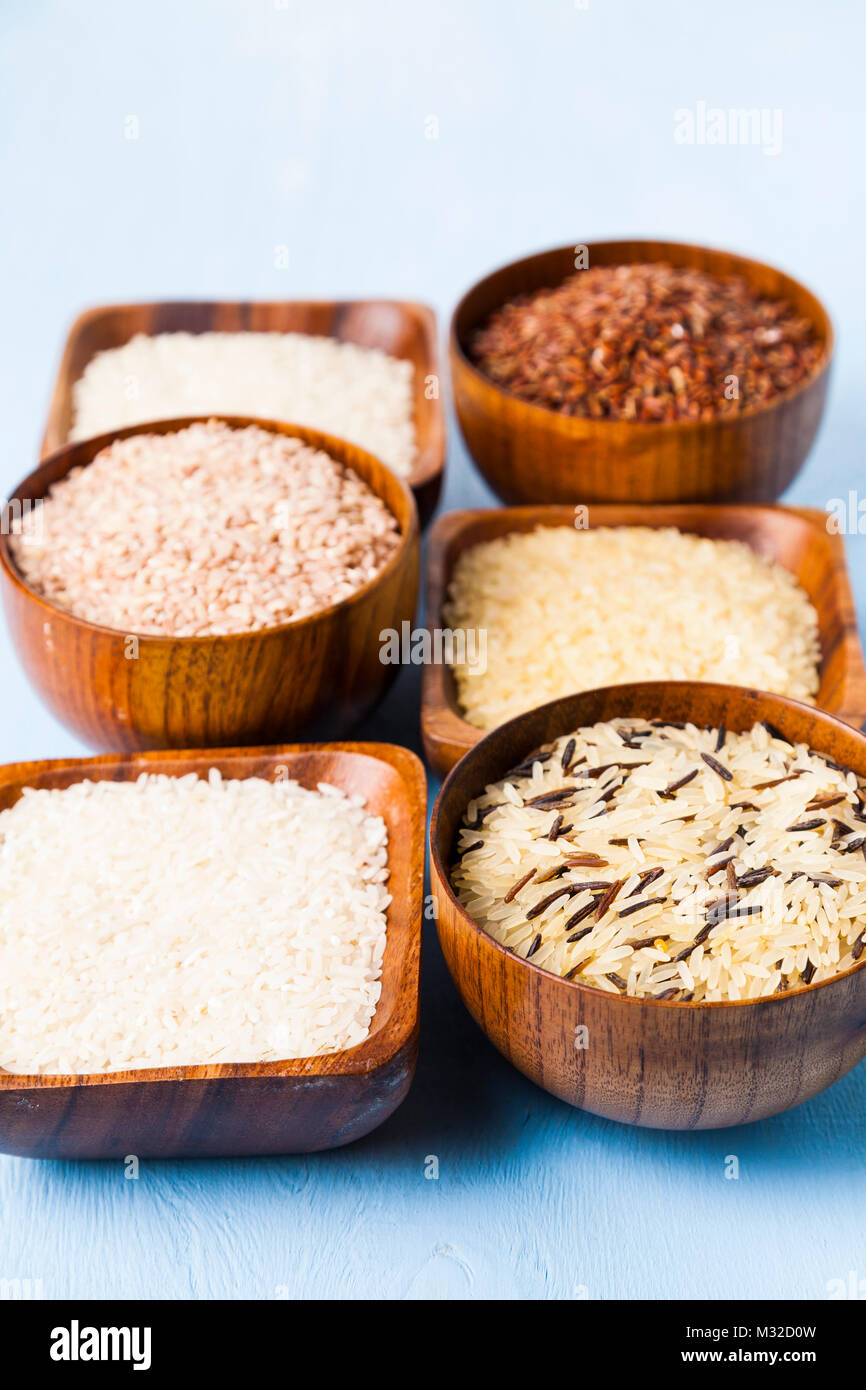 Sechs Schüsseln mit verschiedenen Sorten von Reis auf einer hölzernen Hintergrund. Zutaten für eine gesunde Ernährung. Stockfoto