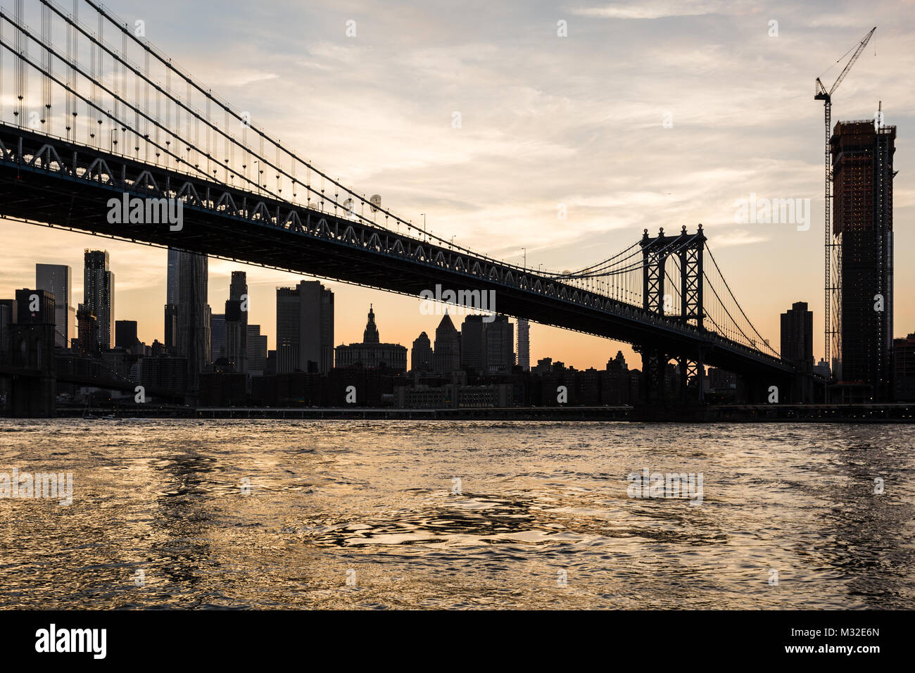 Einen atemberaubenden Sonnenuntergang über die Manhattan Bridge und Manhattan Financial District über dem East River aus Brooklyn in New York City, USA Stockfoto