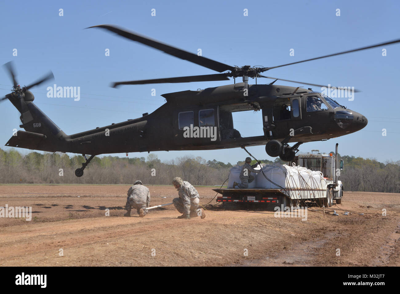 Louisiana National Guard Soldaten des 225Th Engineer Brigade verbinden 1.500 Pfund super Säcke zum Ende einer UH-60M Black Hawk zu schleudern werden von Piloten aus der Army Aviation Support #3 in Pineville, La geladen, in Bayou Darrow südlich von Colfax in Grant Parish, La Die super Säcke werden verwendet, um den Fluss von Wasser, bei denen eine Steuerung fehlgeschlagen zu verlangsamen, 14. März 2016. Mehr als 1.400 Gardisten haben die Flut kämpfen über Louisiana unterstützt. (U.S. Army National Guard Foto von 1 Lt. Rebekka Malone) La Wachposten Sling-Laden super Säcke in der Struktur durch Louisian fehlgeschlagen Stockfoto