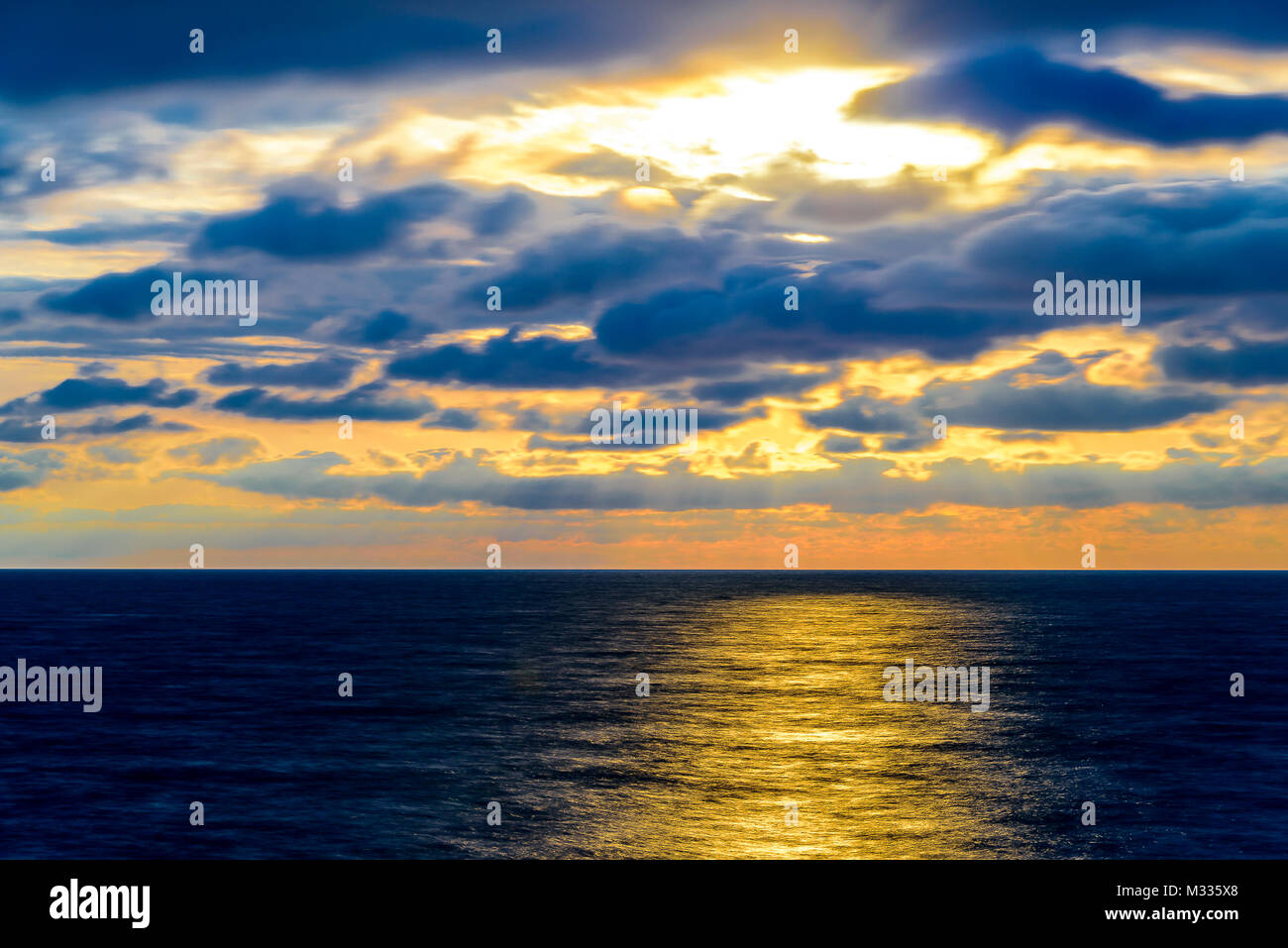 Stilisierte lange Belichtung Sonnenuntergang Meereslandschaft mit verschiedenen Schattierungen von rot, orange, gelb und blau. Stockfoto