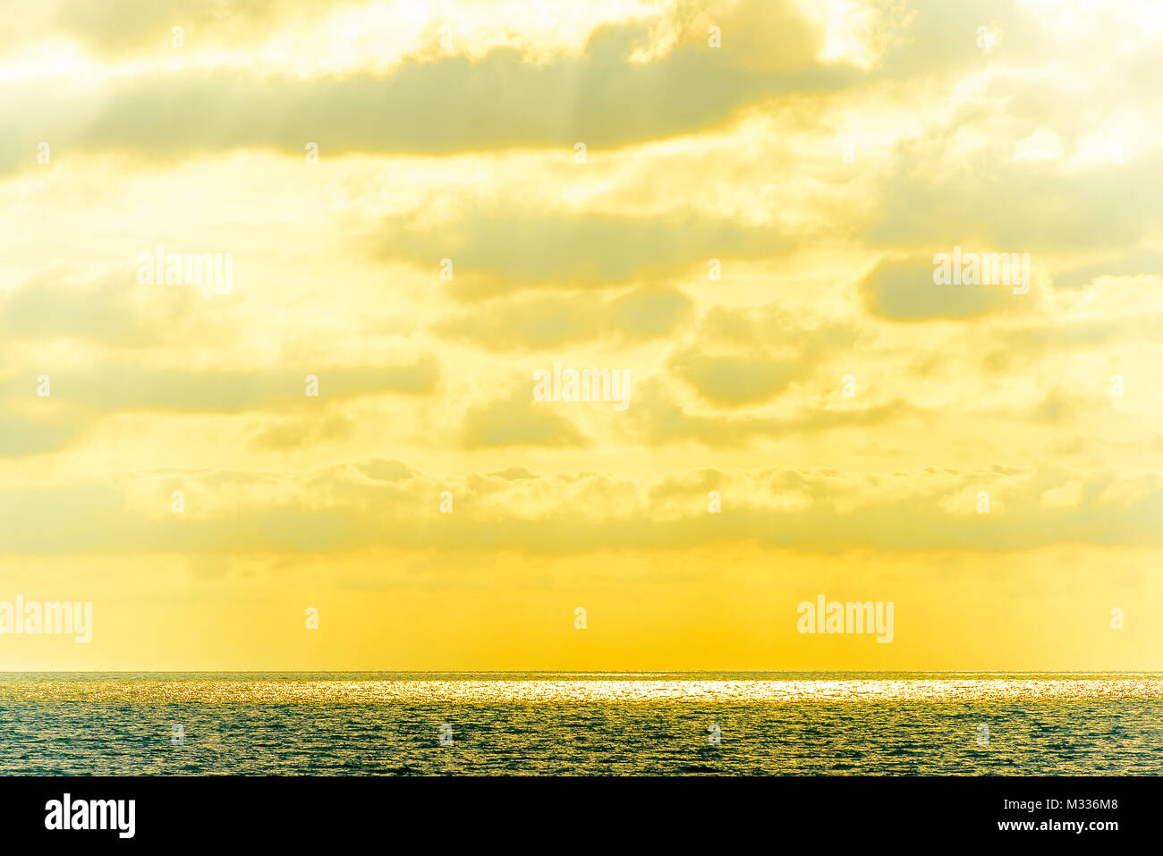 Stilisierte abstrakte Landschaft seascape Sonnenuntergang lange Belichtung mit Wolken unter verschiedenen Schattierungen von Blau, Orange, Gelb und Rot Stockfoto