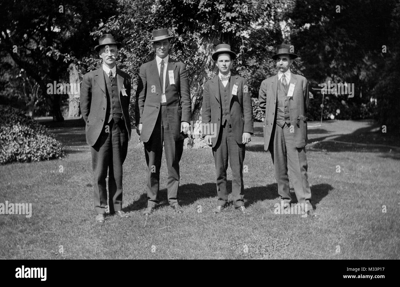 Vier reife Männer mit Bändern auf Ständer für Portrait, Ca. 1925. Stockfoto
