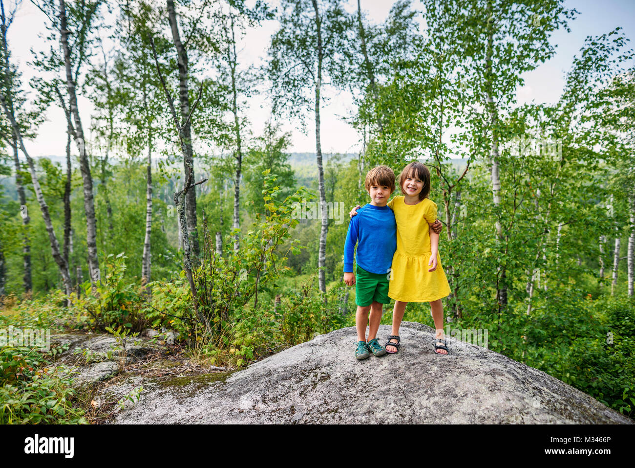 Junge und Mädchen stehend auf einem Felsen im Wald Stockfoto