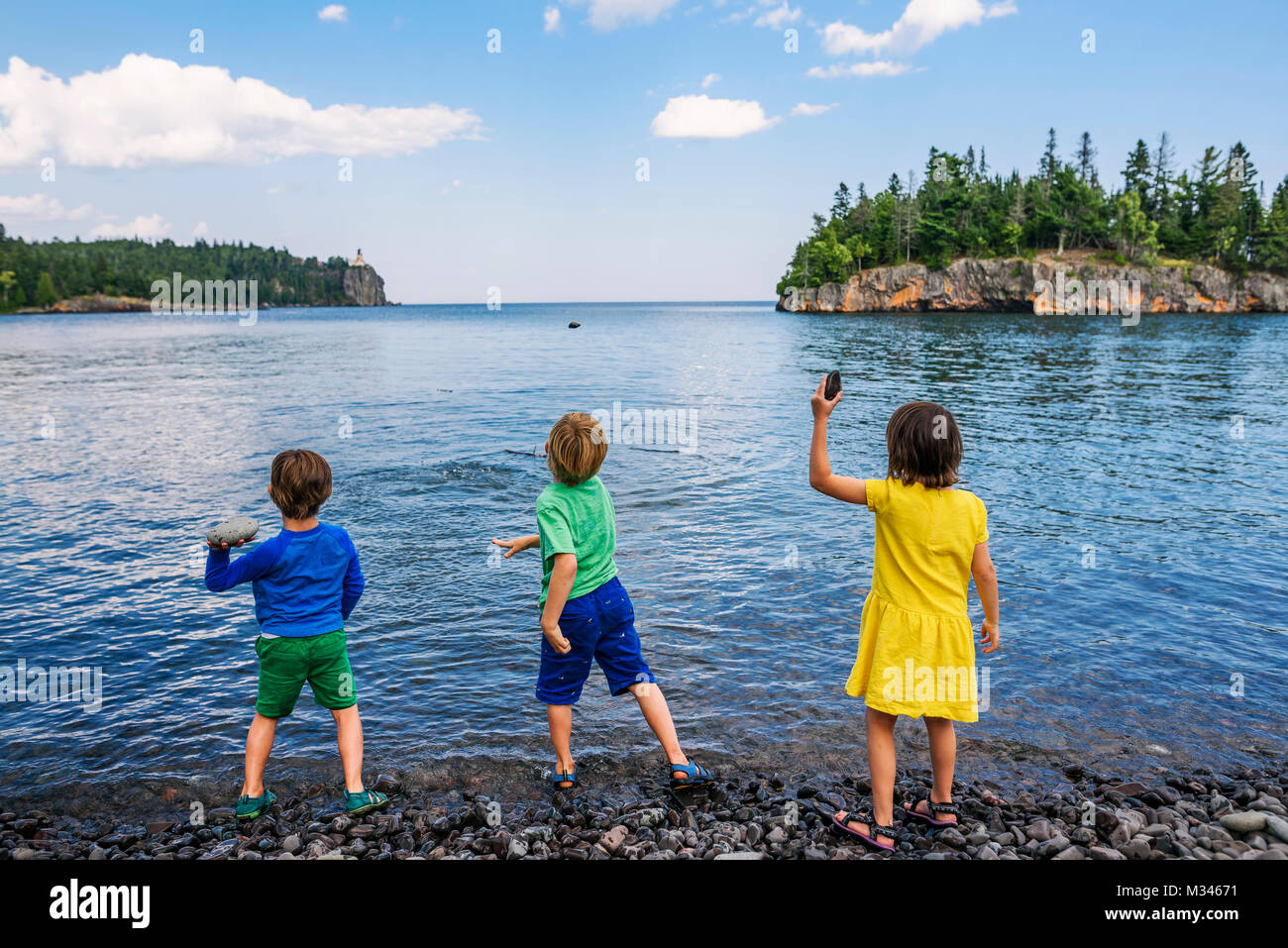 Drei Kinder werfen Steine in den See Stockfoto