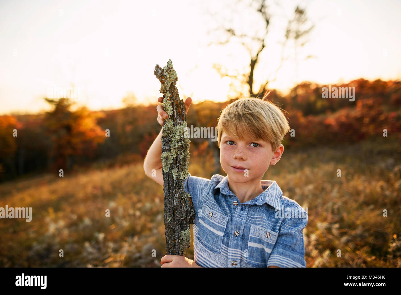 Junge in einem Feld mit einem Stück Holz Stockfoto