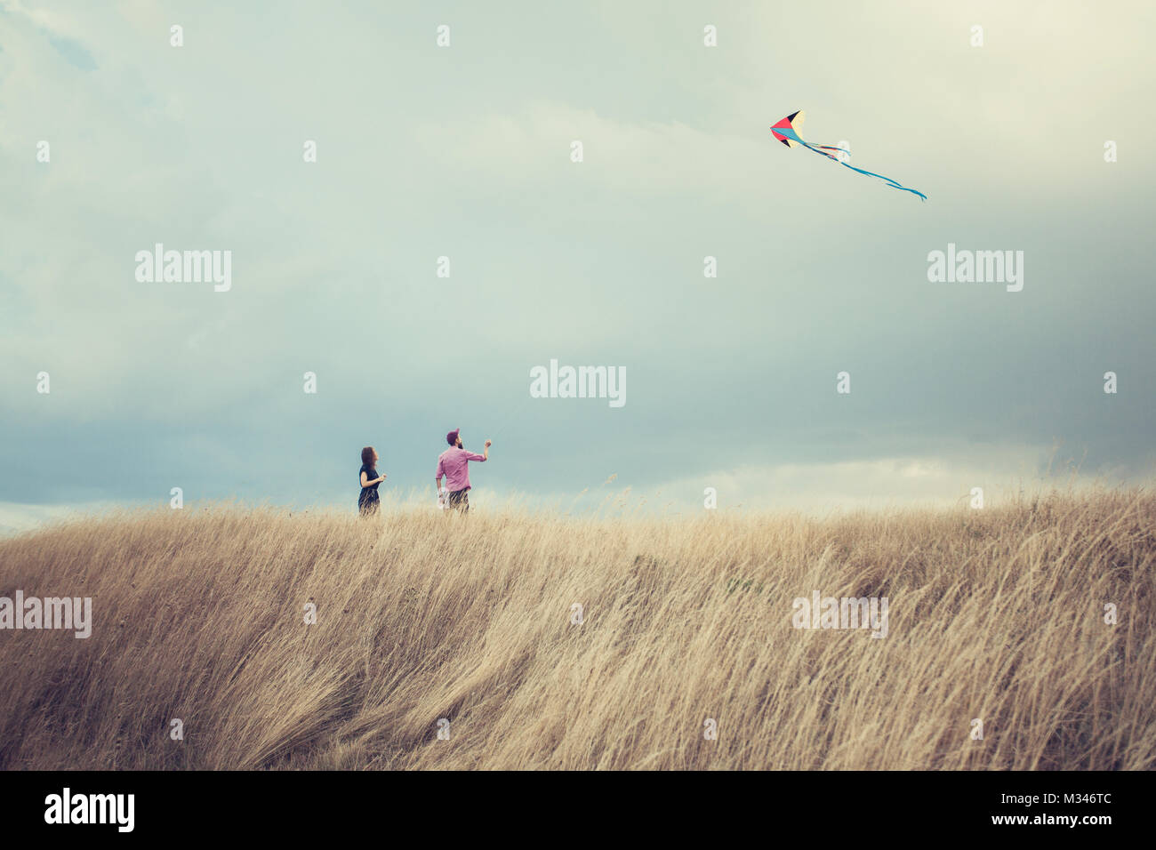 Mann und Frau stehen in einem Feld flying a Kite Stockfoto