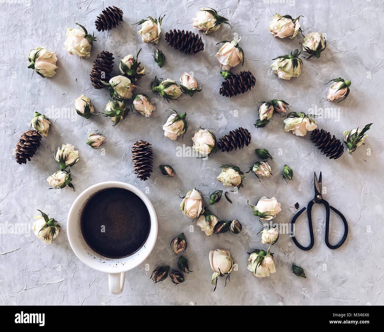 Tasse Kaffee umgeben von Tannenzapfen und Rosenblütenblätter Stockfoto