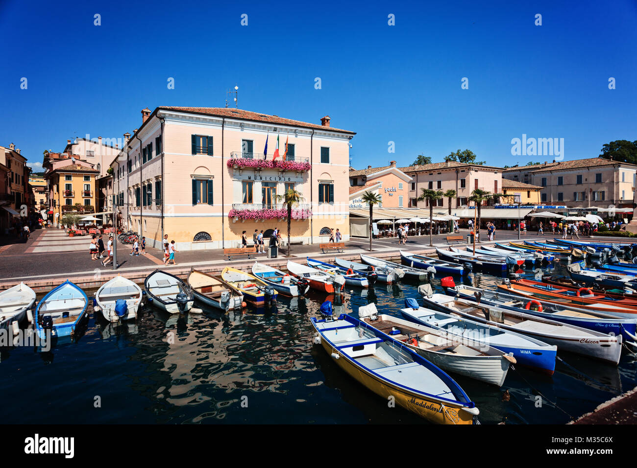 BARDOLINO, Italien, 30. JUNI 2013: Leute gehen vor der City Hall und Boot parken in der Nähe von Bardolino Gardasee Stockfoto