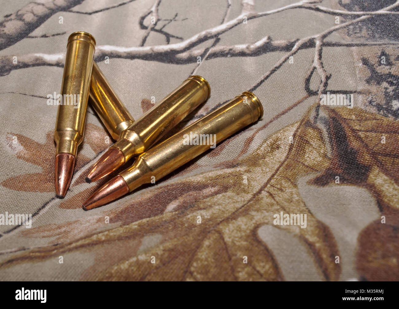 Vier Gewehrkugeln auf eine Camouflage Hintergrund Stockfoto