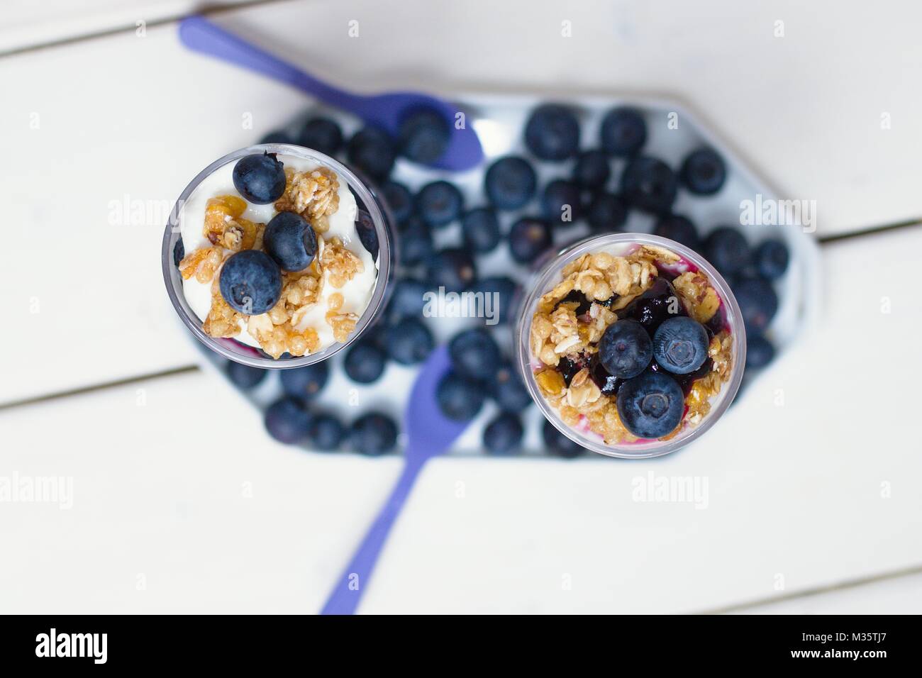 Top down Sicht auf zwei heidelbeere Joghurt Parfaits in hohe Gläser auf weissem Holztisch Stockfoto