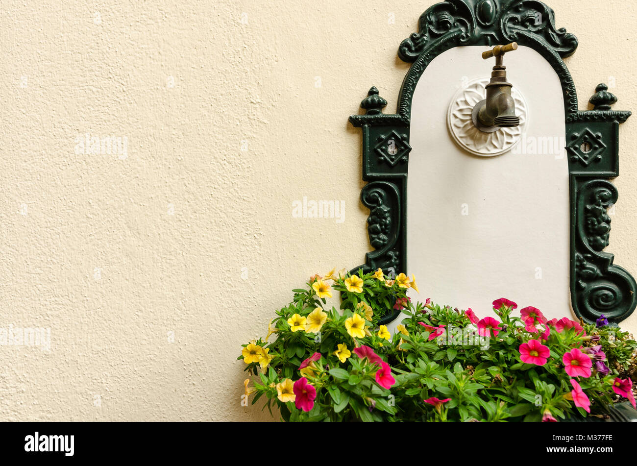 Eine antike verzierten Brunnen mit Gusseisen Einrichtung an der Wand mit  einem bunten Blumen Stockfotografie - Alamy
