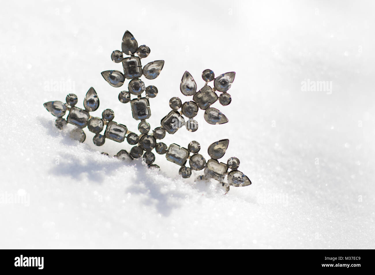 Glitzernde Schneeflocken Ornament in frischem Pulverschnee an einem sonnigen Tag. Stockfoto