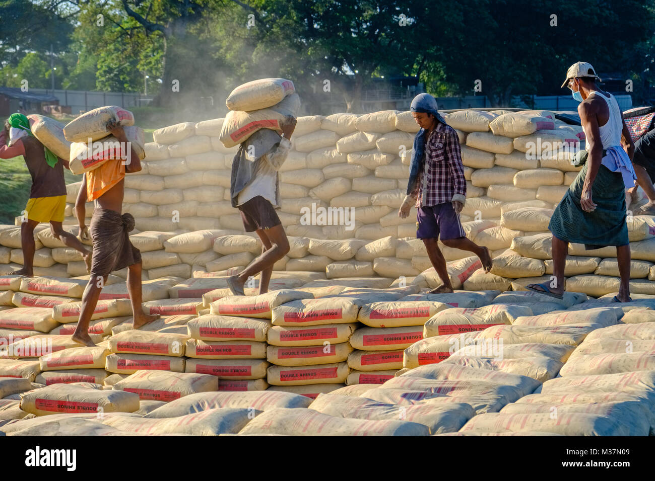 Arbeitnehmer sind laden Zementsäcke auf einem Boot im Hafen am Rande der Stadt auf dem Irrawaddy Fluss Stockfoto