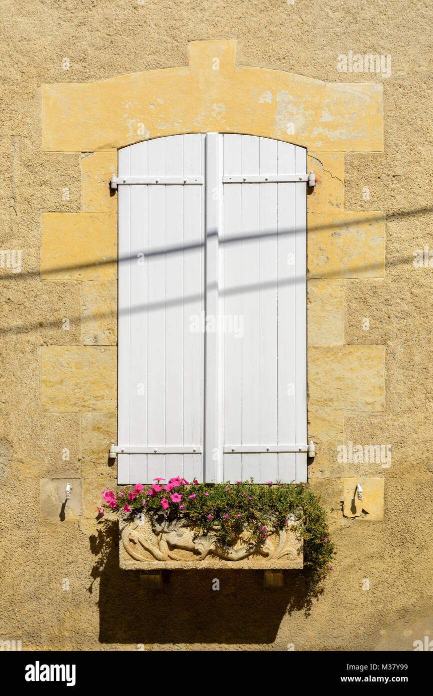 Fenster mit weißen Fensterläden aus Holz und Blumen auf einem Gebäude in Valence-sur-Baïse, Gers (Gascogne), Occitanie (Midi-Pyrénées), im Südwesten von Frankreich Stockfoto