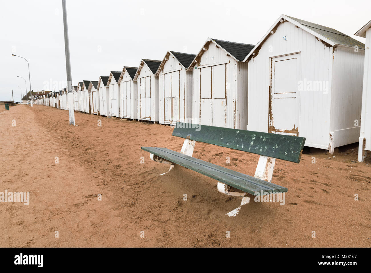 Eine Bank und weißen Badestrand Häuser, Hütten in einer Reihe am Strand Stockfoto