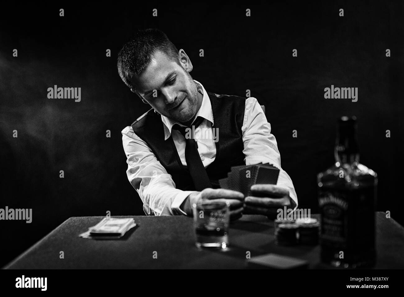 Harter Kerl spielen seine Karten in der Nähe von seiner Brust am Pokertisch Stockfoto