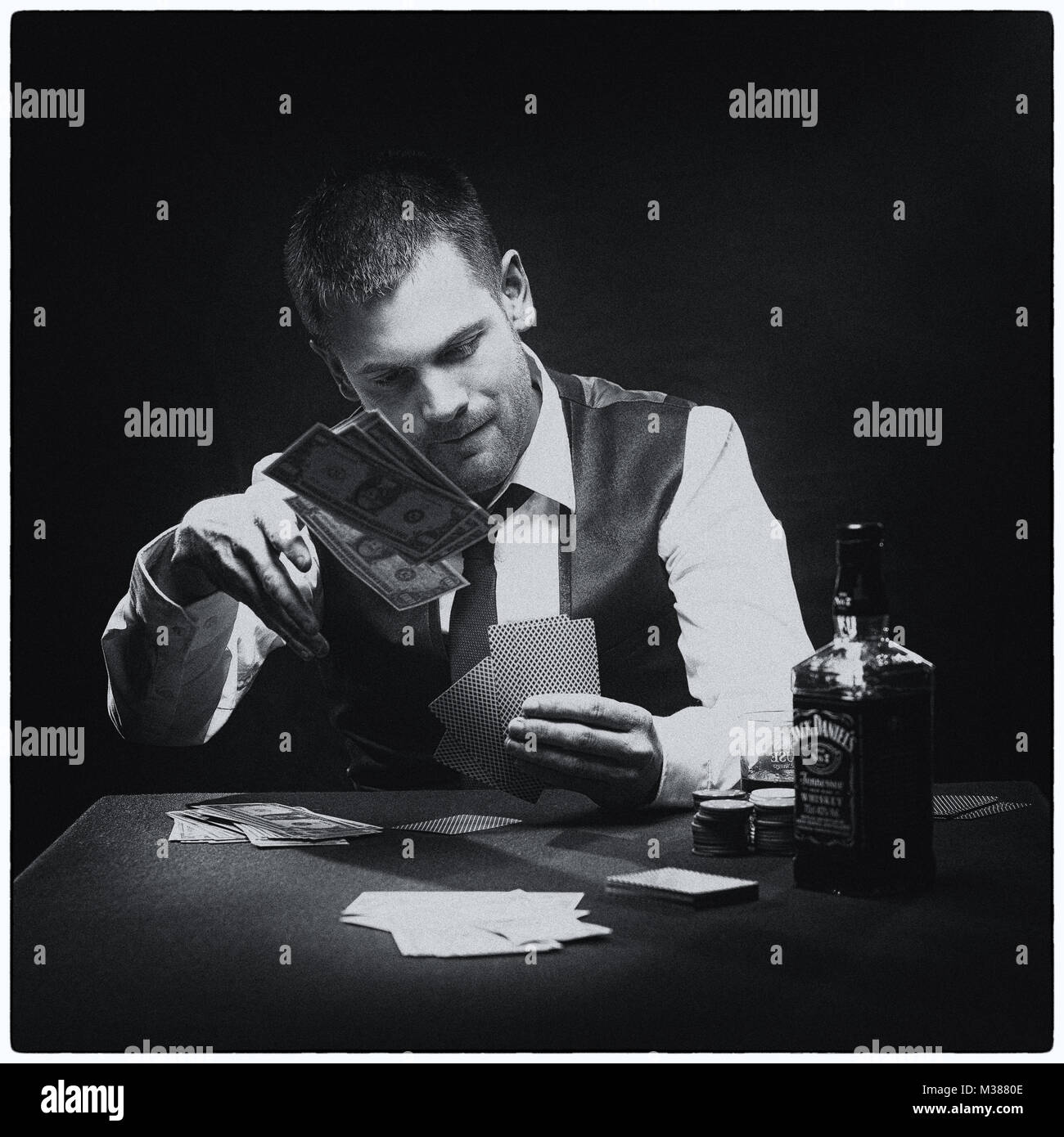 Harter Kerl spielen seine Karten in der Nähe von seiner Brust am Pokertisch Stockfoto