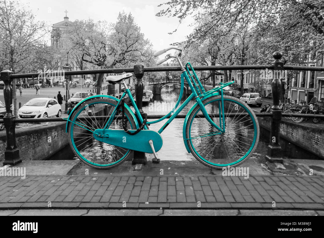 Ein Bild von einem einsamen Azure Bike auf der Brücke über den Kanal in Amsterdam. Der Hintergrund ist schwarz und weiß. Stockfoto