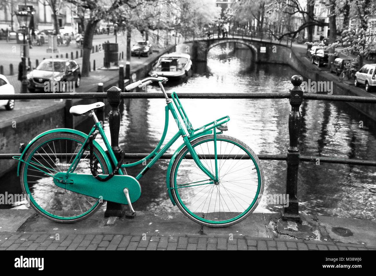 Ein Bild von einem einsamen Azure Bike auf der Brücke über den Kanal in Amsterdam. Der Hintergrund ist schwarz und weiß. Stockfoto