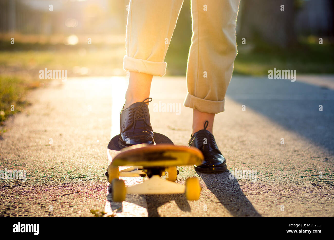 Weibliche reiten ein Skateboard bei Sonnenuntergang. Stadt urban Lifestyle Stockfoto