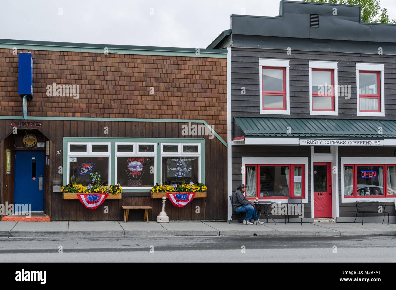 Vom 6. Juli 2017 - Haines, Alaska, USA; amerikanische Kleinstadt kulturellen Momentaufnahme der sitzenden Person außerhalb Coffee Shop neben der Bar. Stockfoto