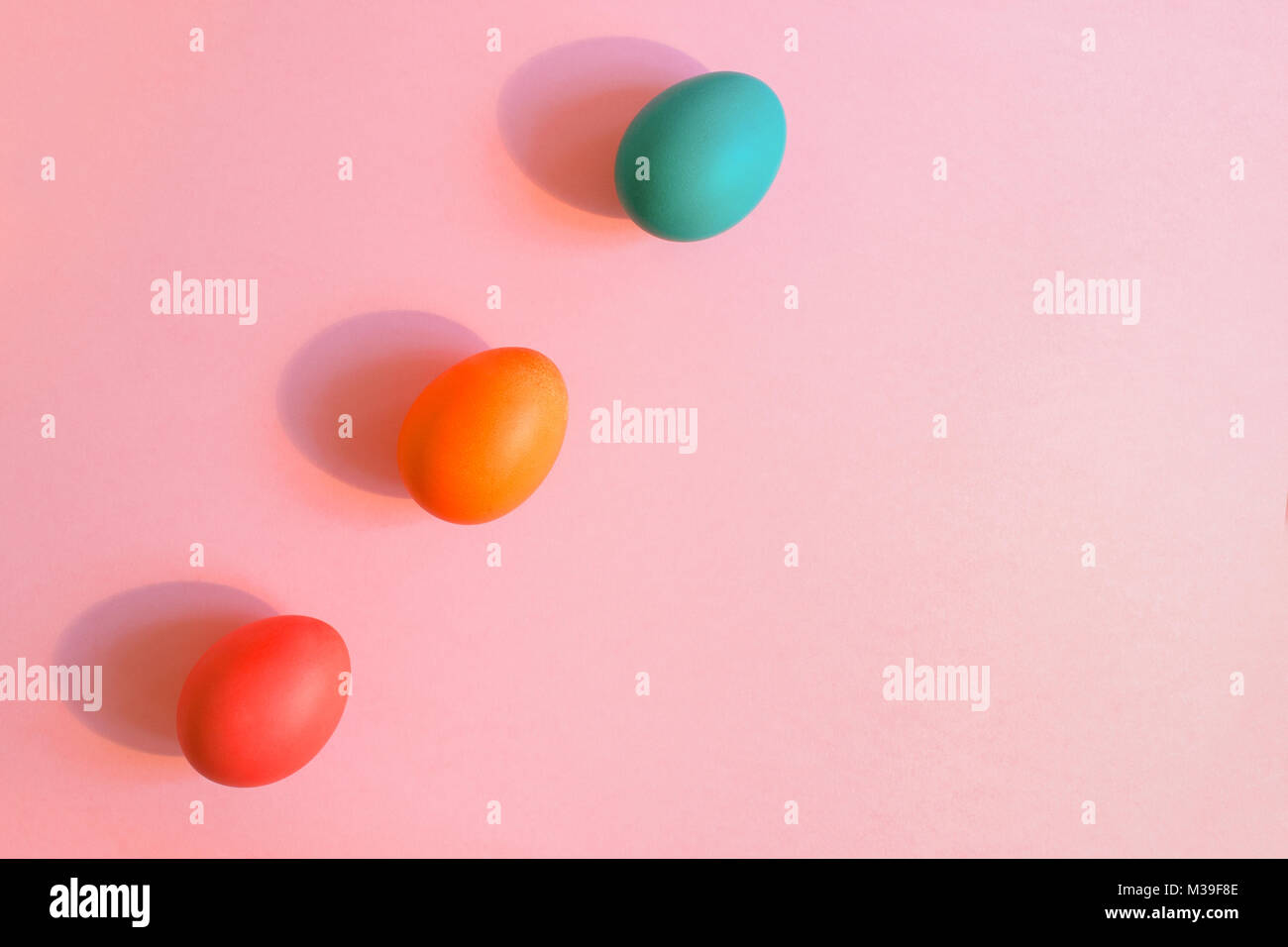 Flach drei Ostern bunt bemalte Eier schräg auf einem rosa Hintergrund mit Kopie Raum liegen. Stockfoto