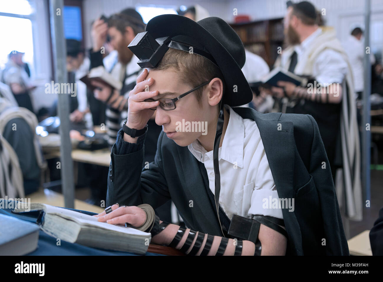 Eine religiöse jüdische Teenager gebetsriemen an Morgengebet Dienstleistungen in Queens, New York, zu tragen. Stockfoto