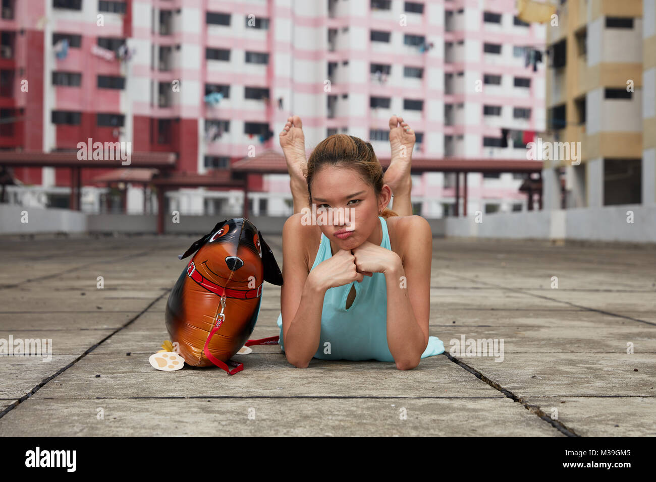 Gerne Spaß - liebevolle junge Tänzerin mit Spielzeug ballon Hund an Rochor Center, Singapur. Diese farbenfrohen Gebäude sind historische Sehenswürdigkeit. Stockfoto