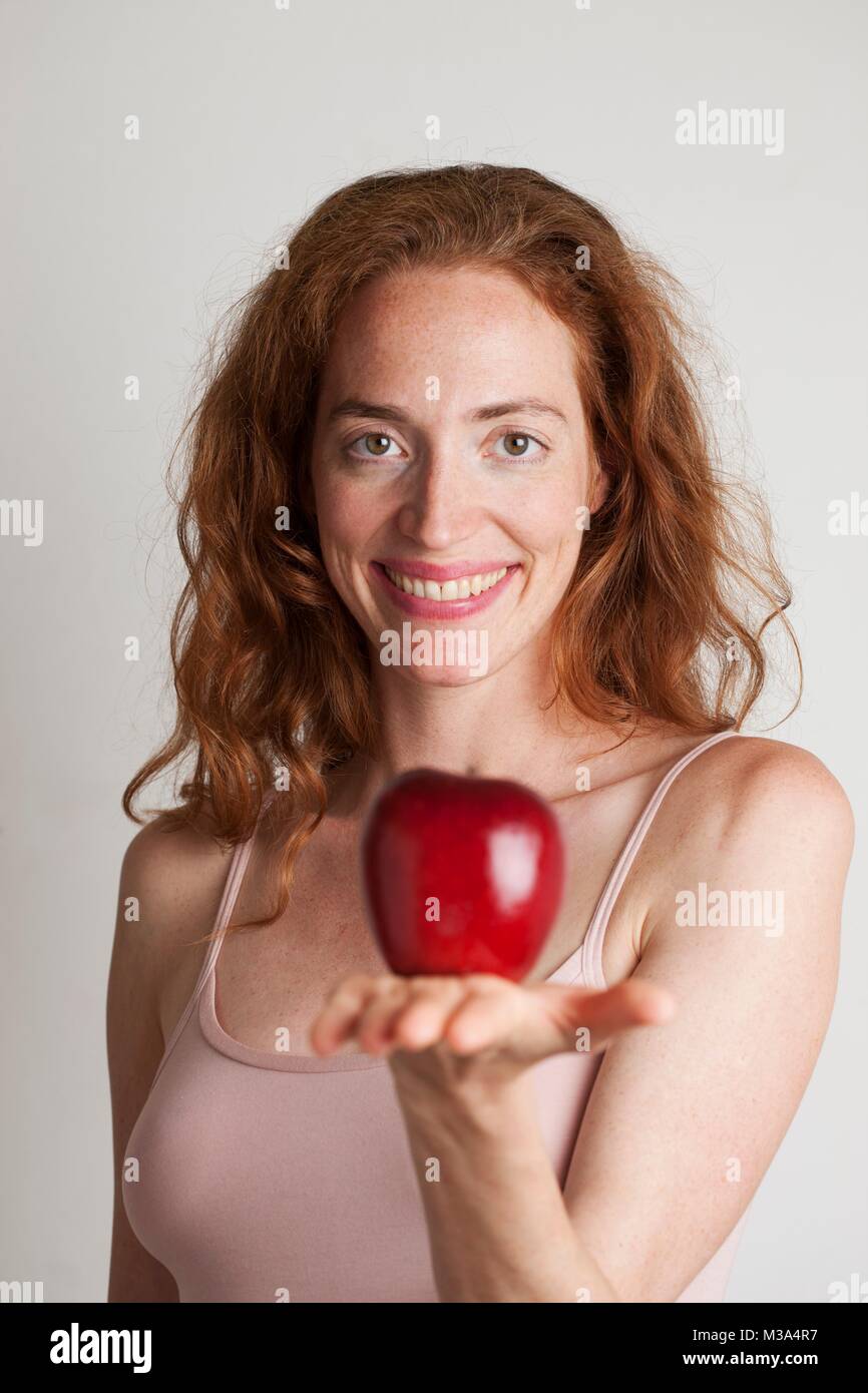 MODEL RELEASED. Portrait von lächelnden Frau mit roten Apfel. Stockfoto