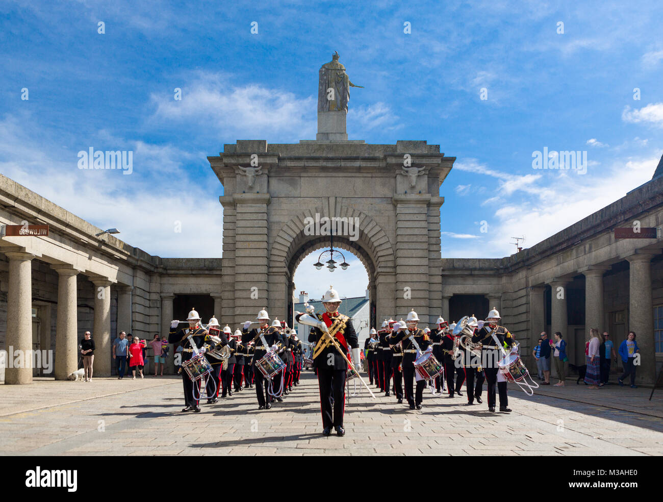 The Band Of HM Royal Marines Marsch durch's Plymouth Royal William Yard Torbogen auf einem hellen, sonnigen Tag. Stockfoto