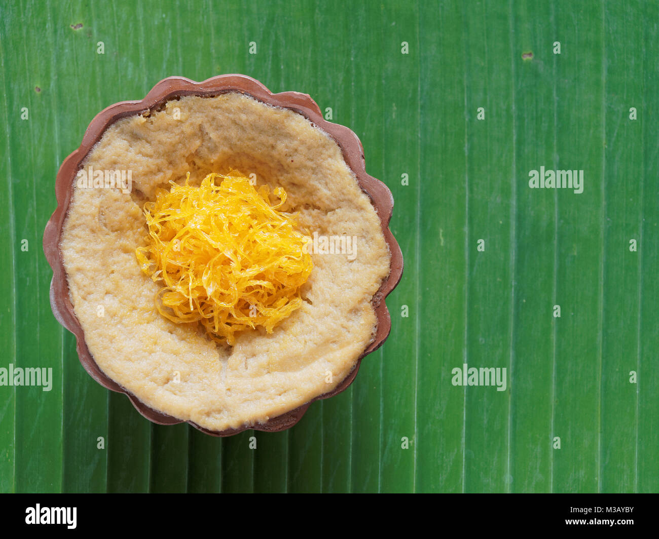 Thailändisches Dessert, Eierstich mit süßen klebrigen Reis garniert mit goldenen Fäden, auf Banana leaf Hintergrund Stockfoto