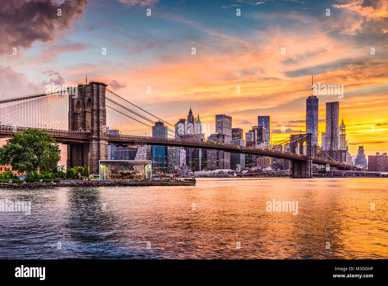 Skyline von New York City auf den East River und die Brooklyn Bridge bei Sonnenuntergang. Stockfoto
