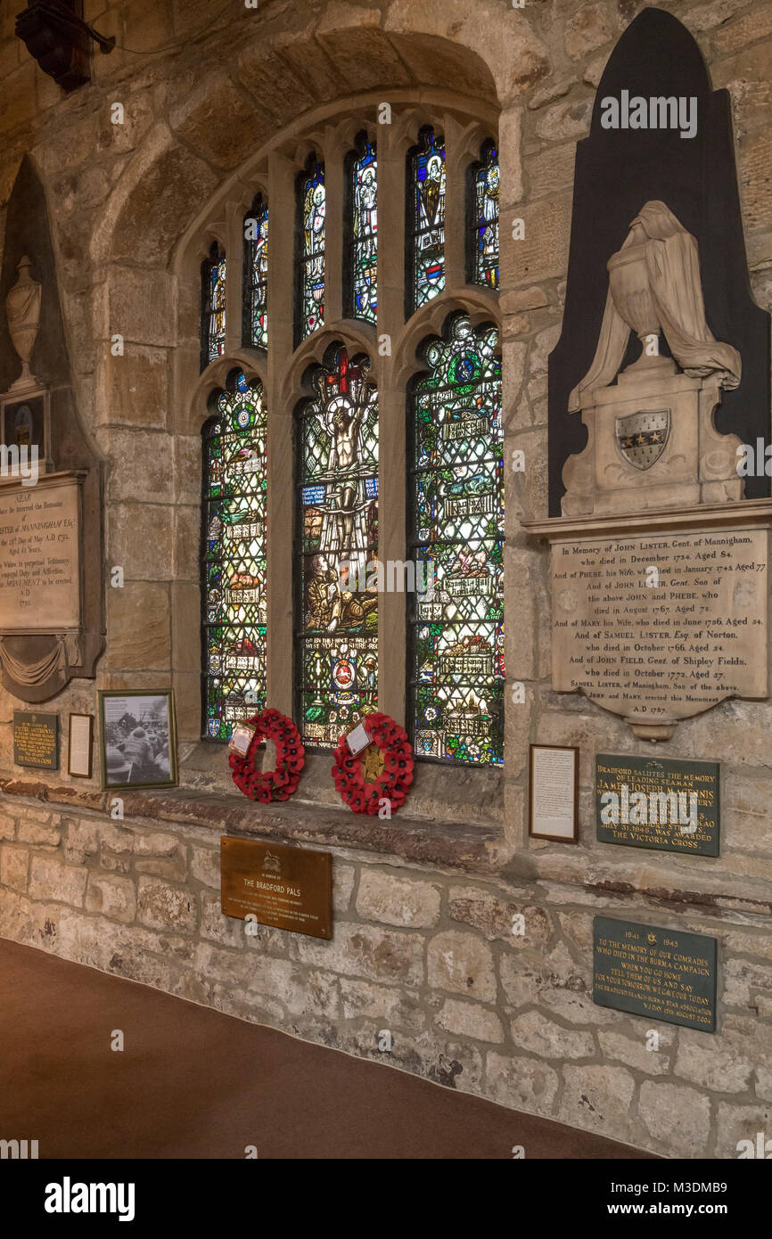 Kleine Ecke von Bradford Cathedral Interieur mit Mohn Kränze unter Glasmalerei WW1 memorial Fenster & Messingschild - West Yorkshire, England, UK. Stockfoto