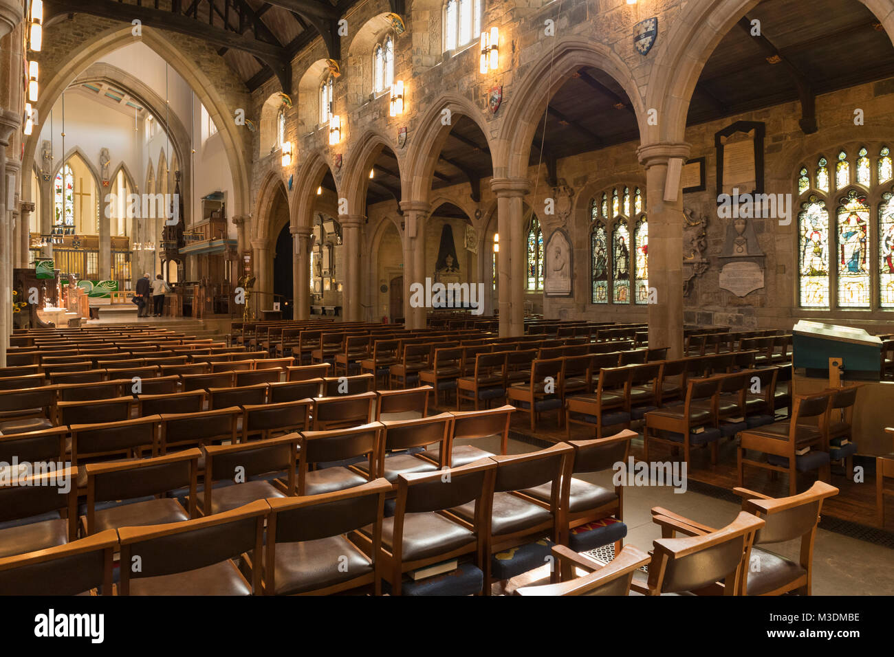 Interieur von Bradford Cathedral, Blick Richtung Osten des Kirchenschiffs mit Steinbögen, Glasfenster und Sitzreihen - West Yorkshire, England, UK. Stockfoto