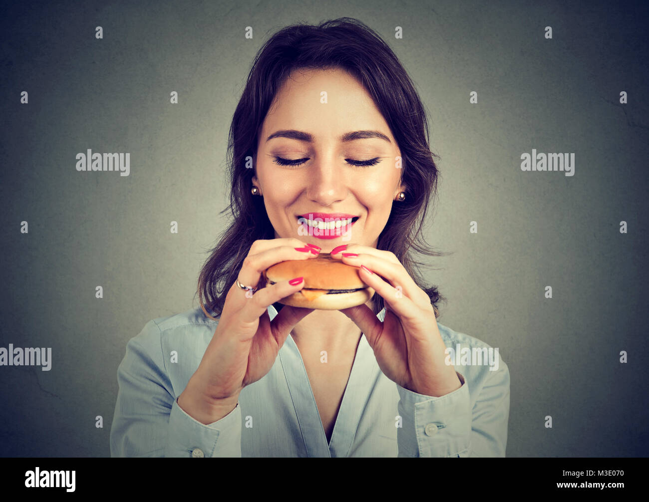 Junge Inhalt Frau mit leckeren Burger im Vorgriff auf den saftigen Geschmack. Stockfoto