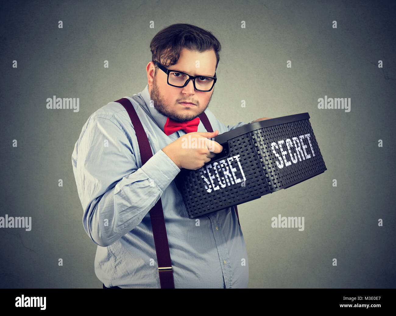 Mollig Mann in Brillen ausblenden Geheimnis in Feld nicht verdächtig an Kamera schaut zu teilen. Stockfoto