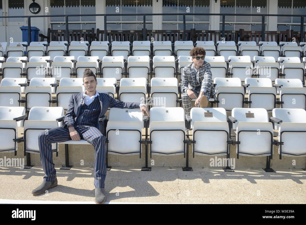 Zwei schöne und gemischten Rennen Kerle tragen maßgeschneiderte Anzüge sind in einem Cricket Ground - die Sonne scheint Stockfoto