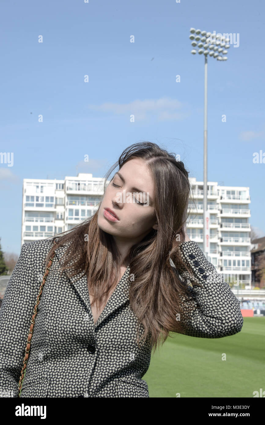 Ein schönes Mädchen mit einem maßgeschneiderten stilvolle gemusterten Anzug ist in einem Cricket Ground an einem schönen hellen Tag - sie ist zuversichtlich und durchsetzungsfähige Stockfoto