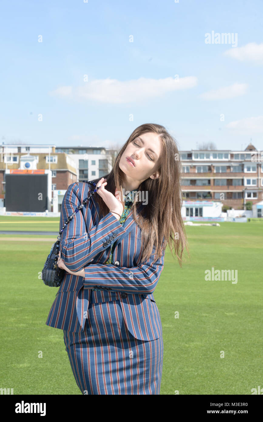 Ein schönes Mädchen mit einem maßgeschneiderten stilvolle gemusterten Anzug ist in einem Cricket Ground an einem schönen hellen Tag - sie ist zuversichtlich und durchsetzungsfähige Stockfoto