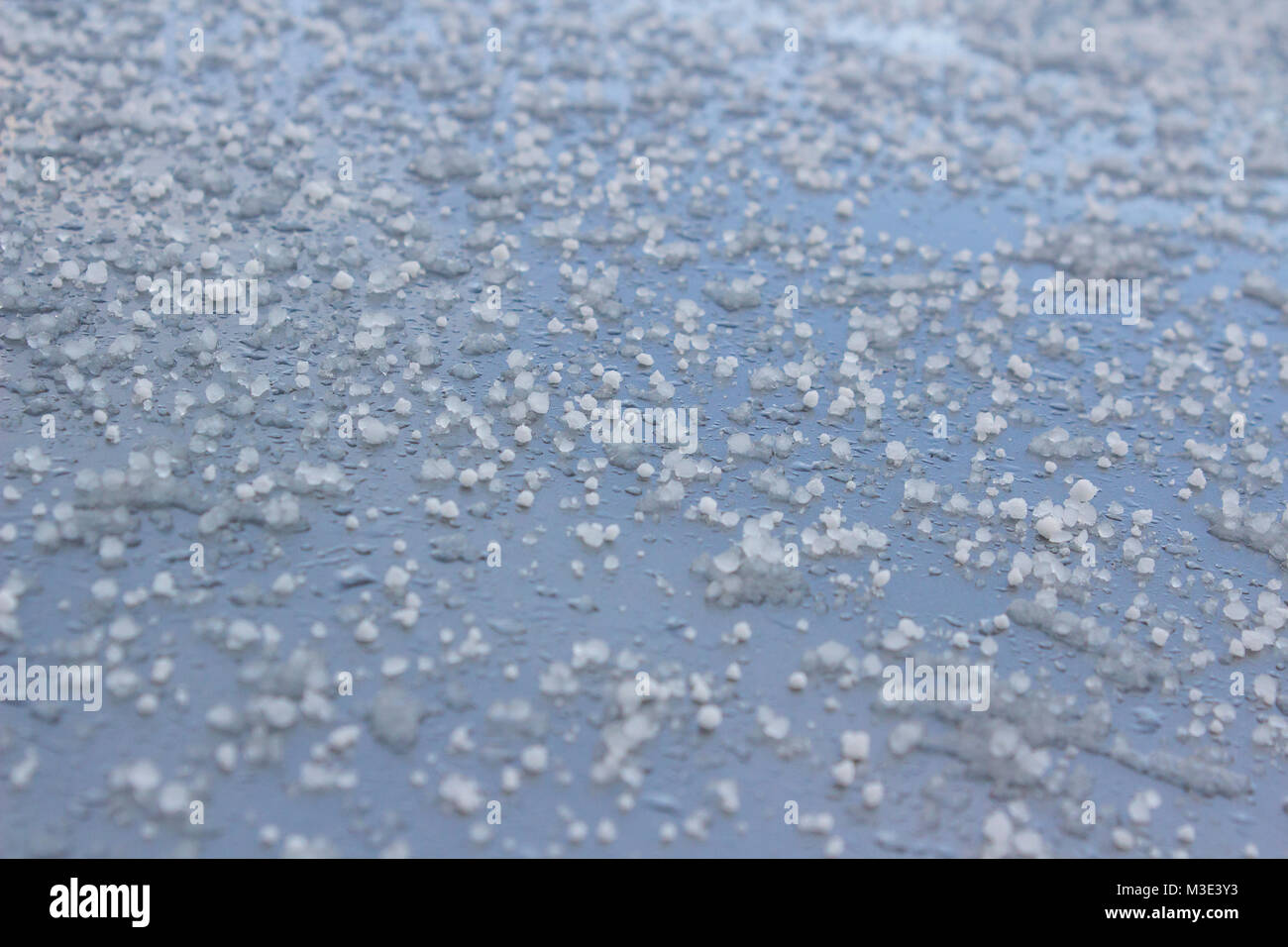 Gefrorene Hagelkörner auf einem silbernen Auto Daches nach einer kalten Dusche Stockfoto